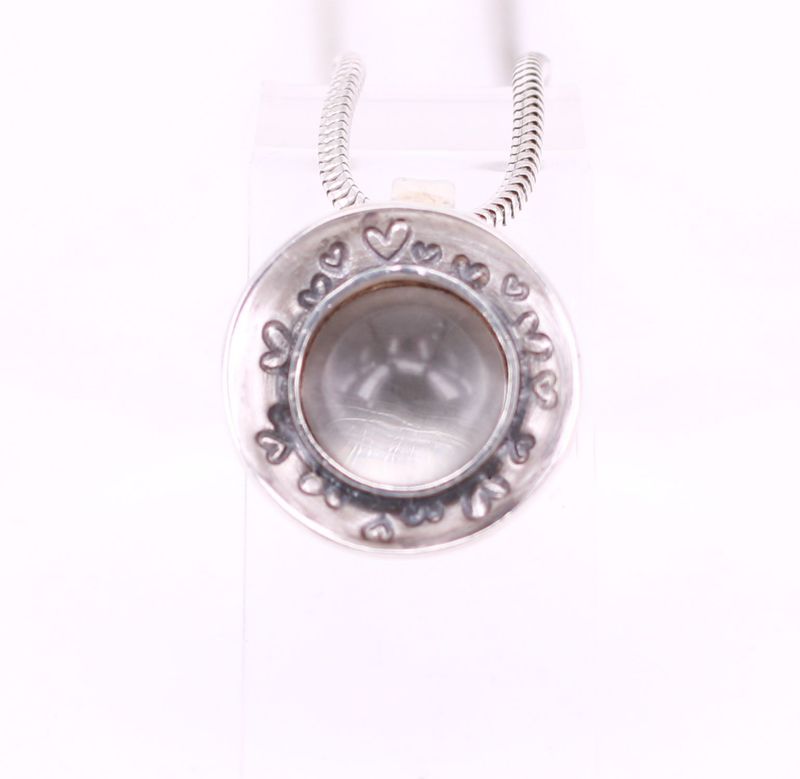 Tierhaare unter rundem Bergkristall in einer Herzschale