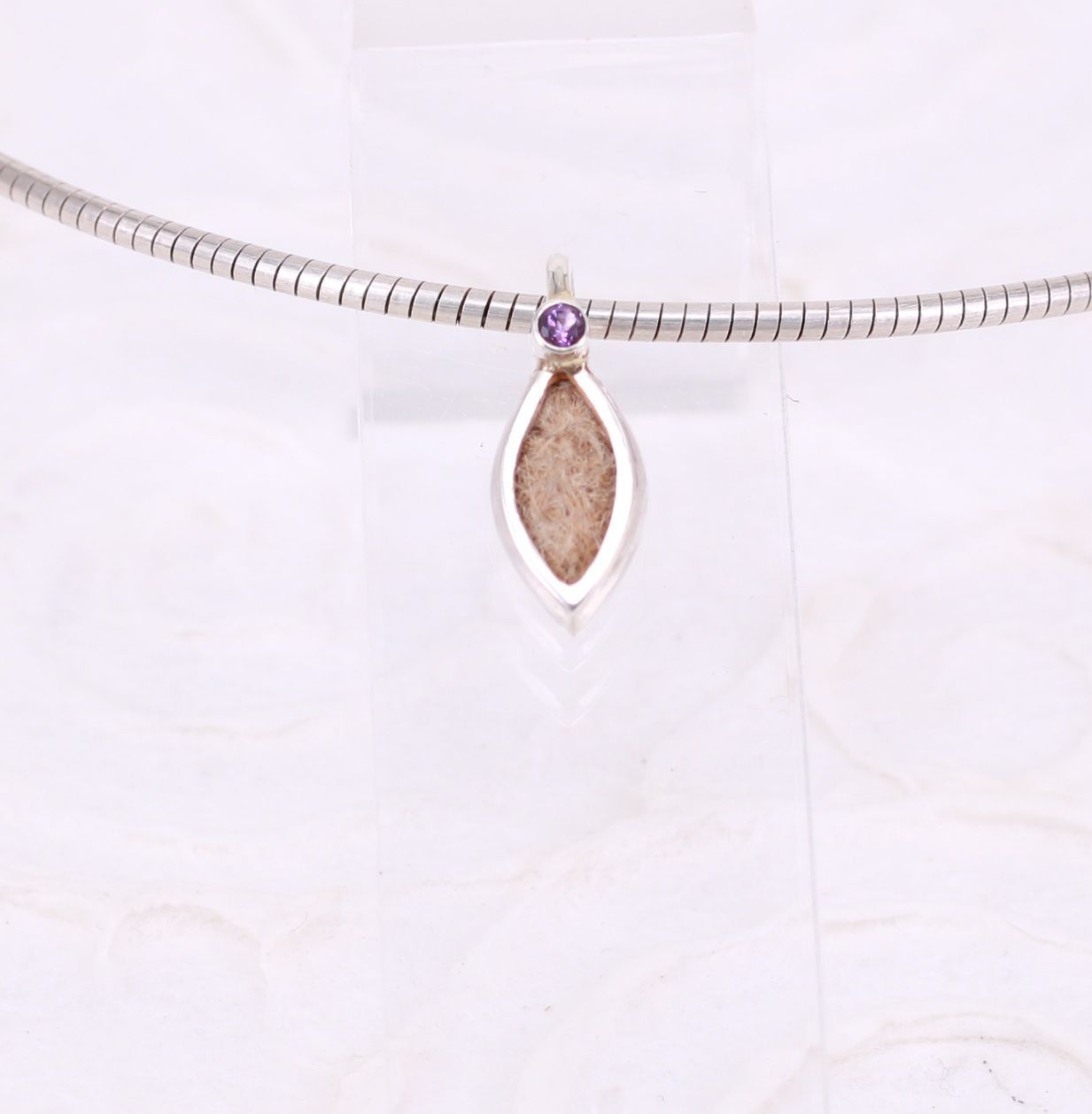 eleganter Kettenanhänger in Navetteform mit eingearbeiteten Tierhaaren und einem funkelnden Edelstein