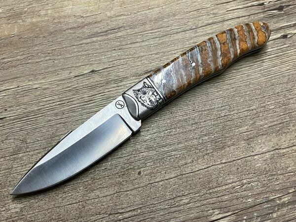 Jagdmesser Vent d`Aubrac, Modell Trapu als Slip Joint Messer, Modell Trapu, erdfarbener Mammutbackenzahn, Mitres mit Wolf und Bison ziseliert Jagdmesser Vent d`Aubrac, Modell Trapu als Slip Joint Messer, Modell Trapu, erdfarbener Mammutbackenzahn, Mitres mit Wolf und Bison ziseliert