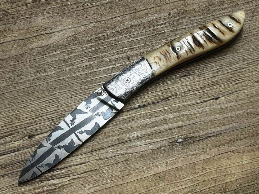Couteau Névé von Tim Bernard, Damaskustaube, Griff Widderhorn, Klinge 300 Lagen Mosaikdamast Taubenmotiv, Mitres graviert,Schlangenlederetui Couteau Névé von Tim Bernard, Damaskustaube, Griff Widderhorn, Klinge 300 Lagen Mosaikdamast Taubenmotiv, Mitres graviert,Schlangenlederetui