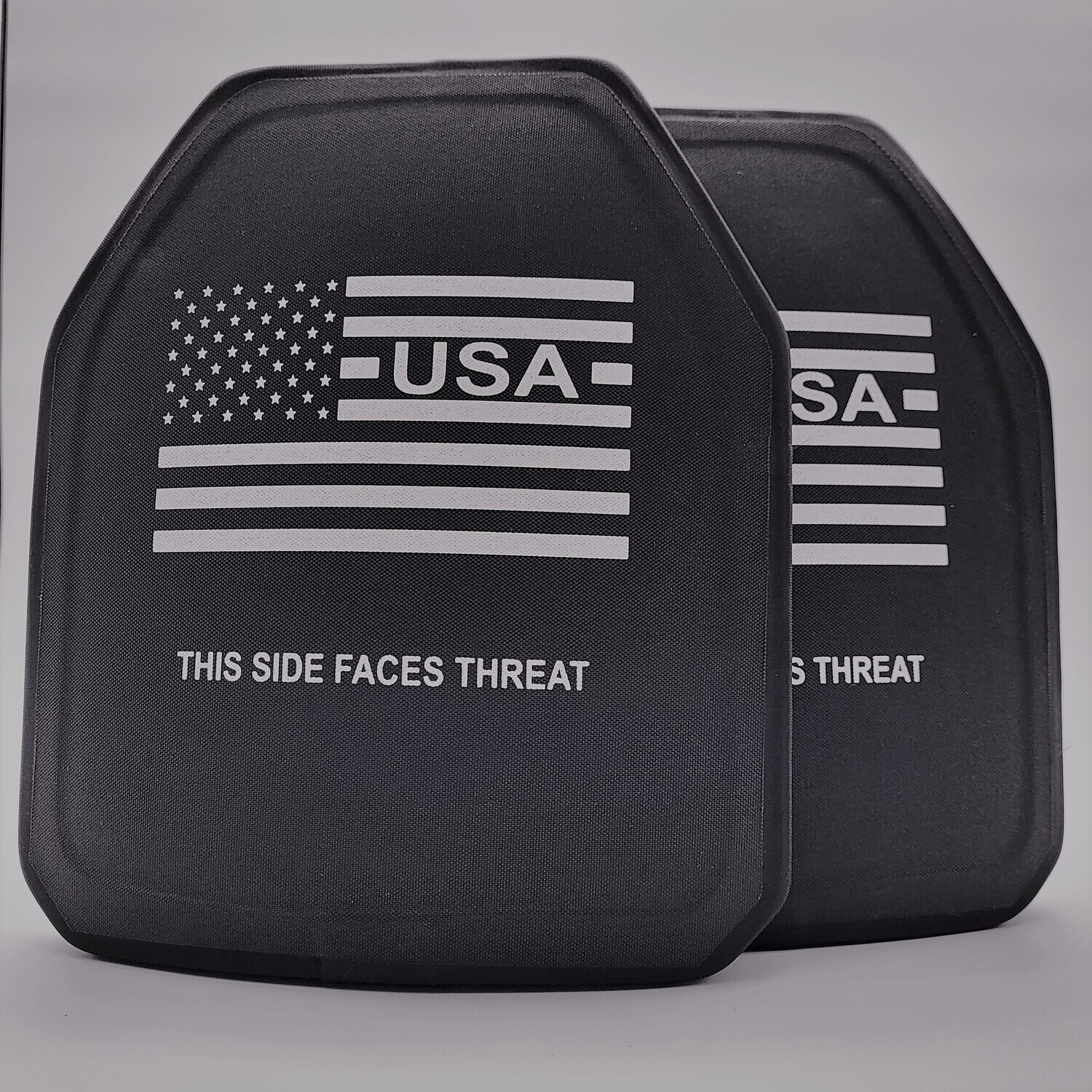 A black Level IV ballistic armor plate designed to stop armor-piercing rifle rounds, offering the highest level of personal protection. The plate features a sleek, multi-curve design for a comfortable fit, along with clearly marked text reading &#39;THIS SIDE FACES THREAT&#39; and a white American flag graphic. Built for tactical professionals, law enforcement, and prepared civilians, this stand-alone plate delivers maximum stopping power in a lightweight, durable construction.