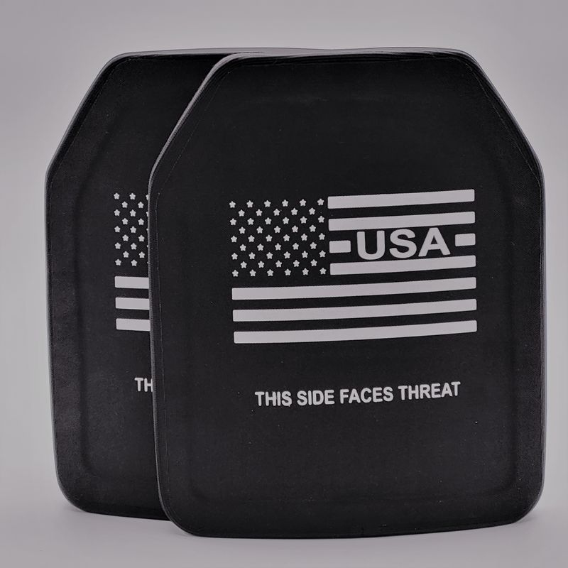 A black Level IV ballistic armor plate with a durable, streamlined design. The plate features a white American flag graphic with the text &#39;USA&#39; below it and the clear instruction &#39;THIS SIDE FACES THREAT&#39; at the bottom. Engineered for maximum protection against armor-piercing rounds while remaining lightweight and ergonomic for enhanced mobility.