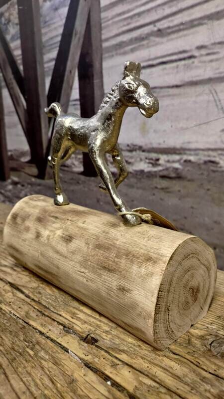 Metalen paard galopperend over boomstam
