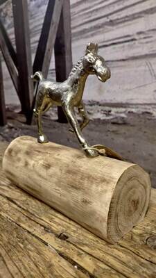 Metalen paard galopperend over boomstam