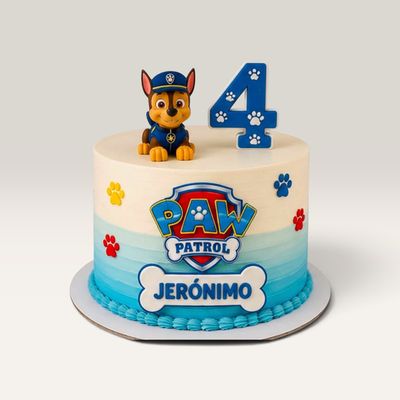 Torta de cumpleaños Paw Patrol con Chase, crema en degradado blanco y azul, huellas de colores y topper con nombre y edad.