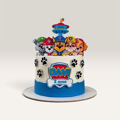 Torta Patrulla Canina personalizada en blanco y azul con cinco cachorros, huellas negras y topper decorativo con nombre y eda