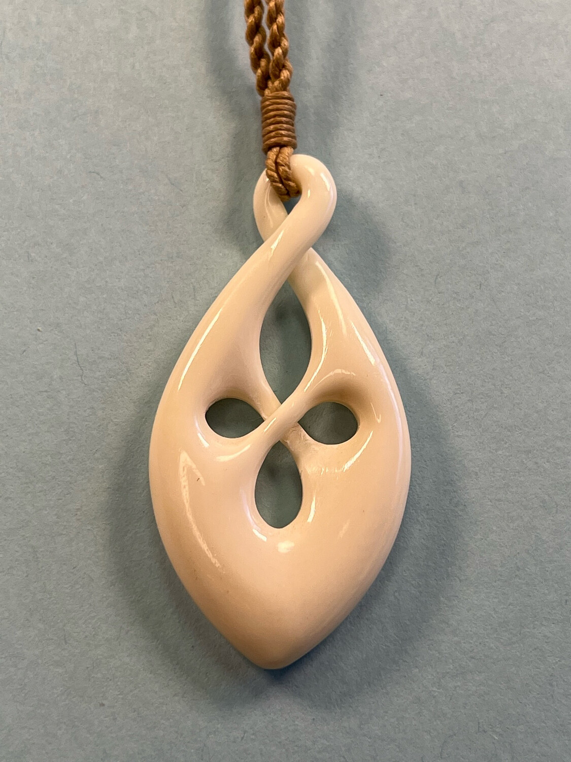 Carved Bone Māori Style Infinity Twist Knot Pendant on Adjustable Hand Braided Tan Cord.