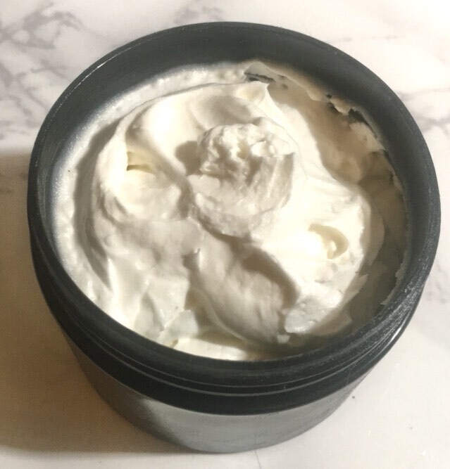 Black jar with white whipped tallow product inside.