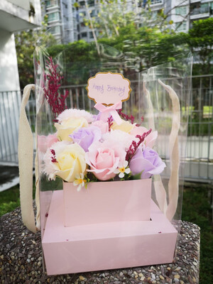Colorful flowers in transparent carrier with tag "Happy birthday"