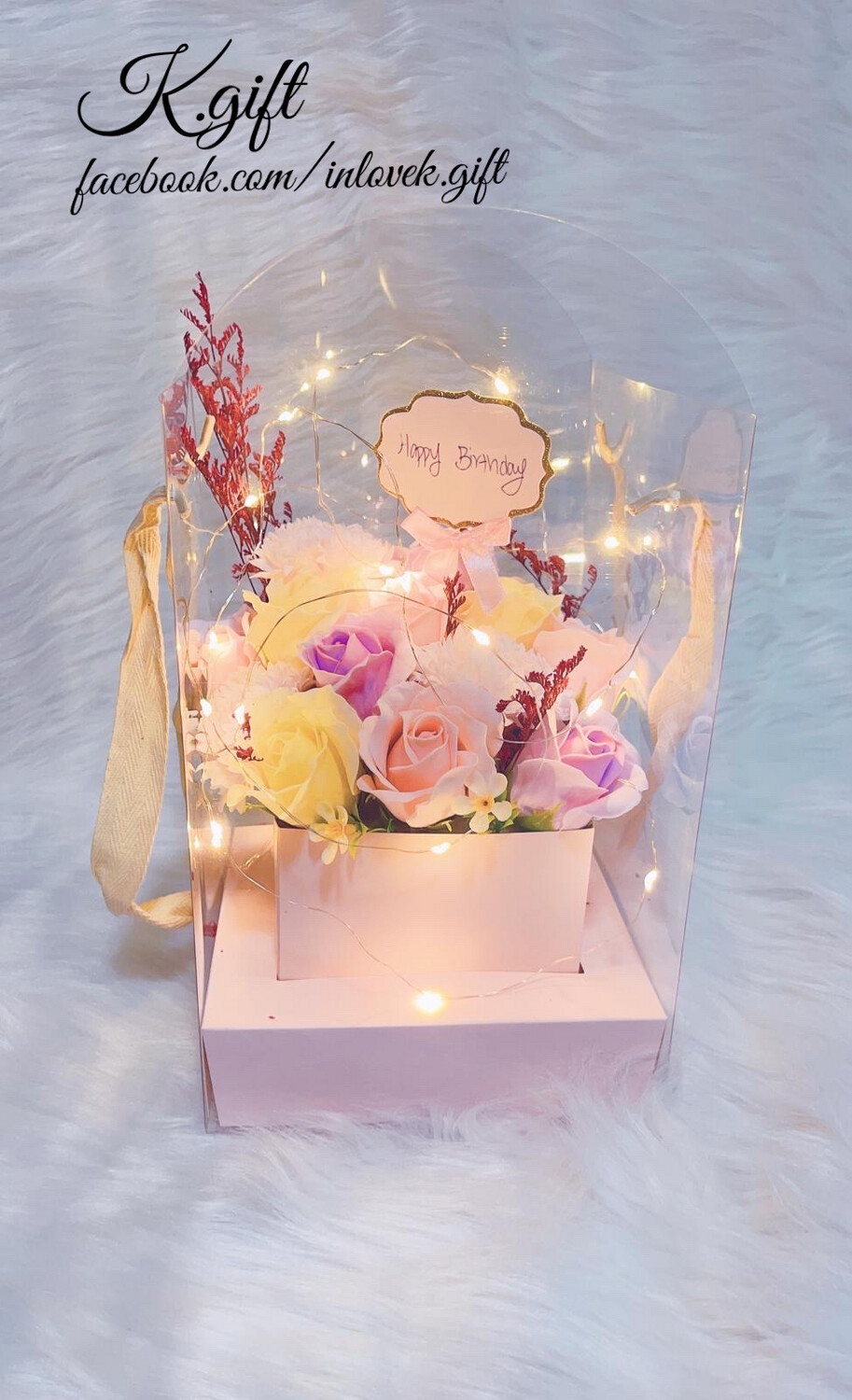 Colorful flowers in transparent carrier with tag &quot;Happy birthday&quot;