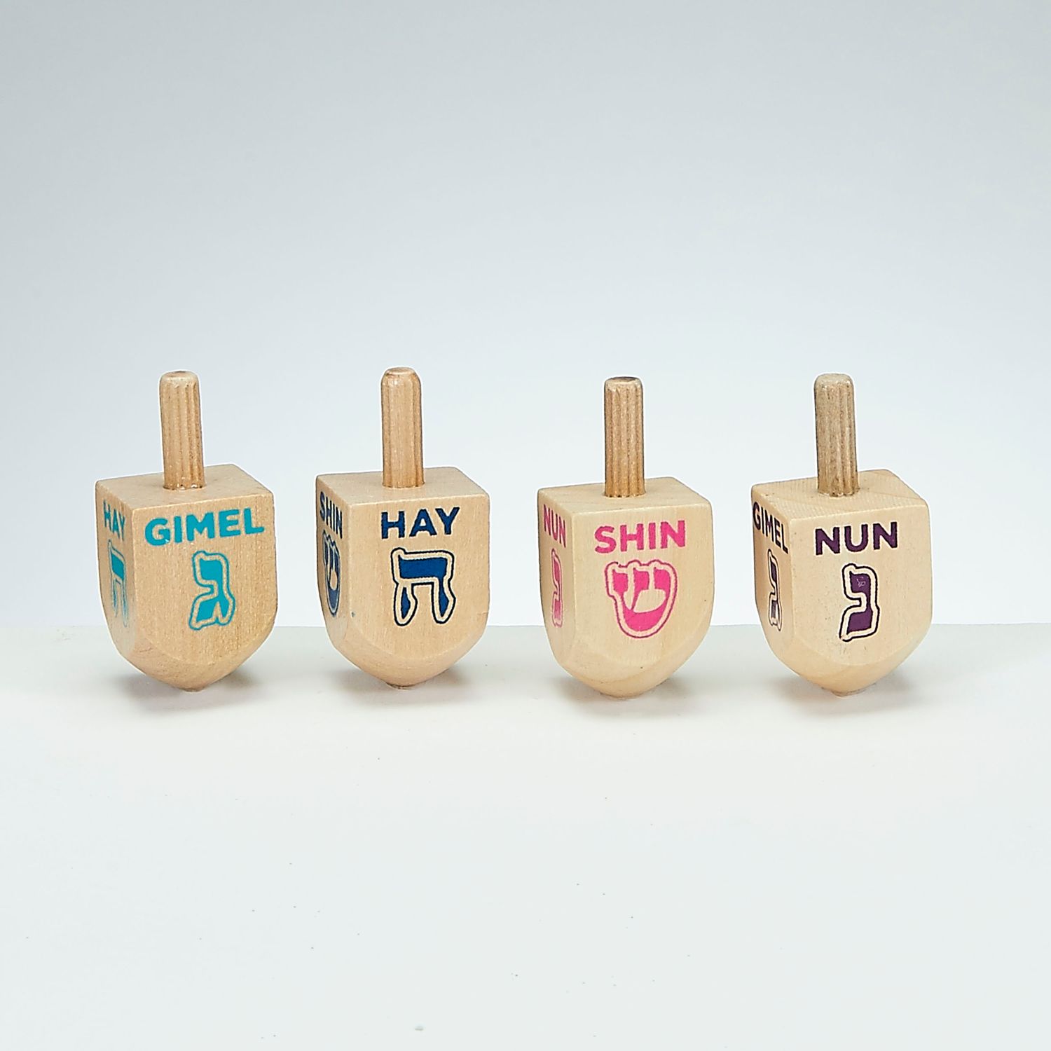 Liten dreidel i tre. Assorterte farger på skriften