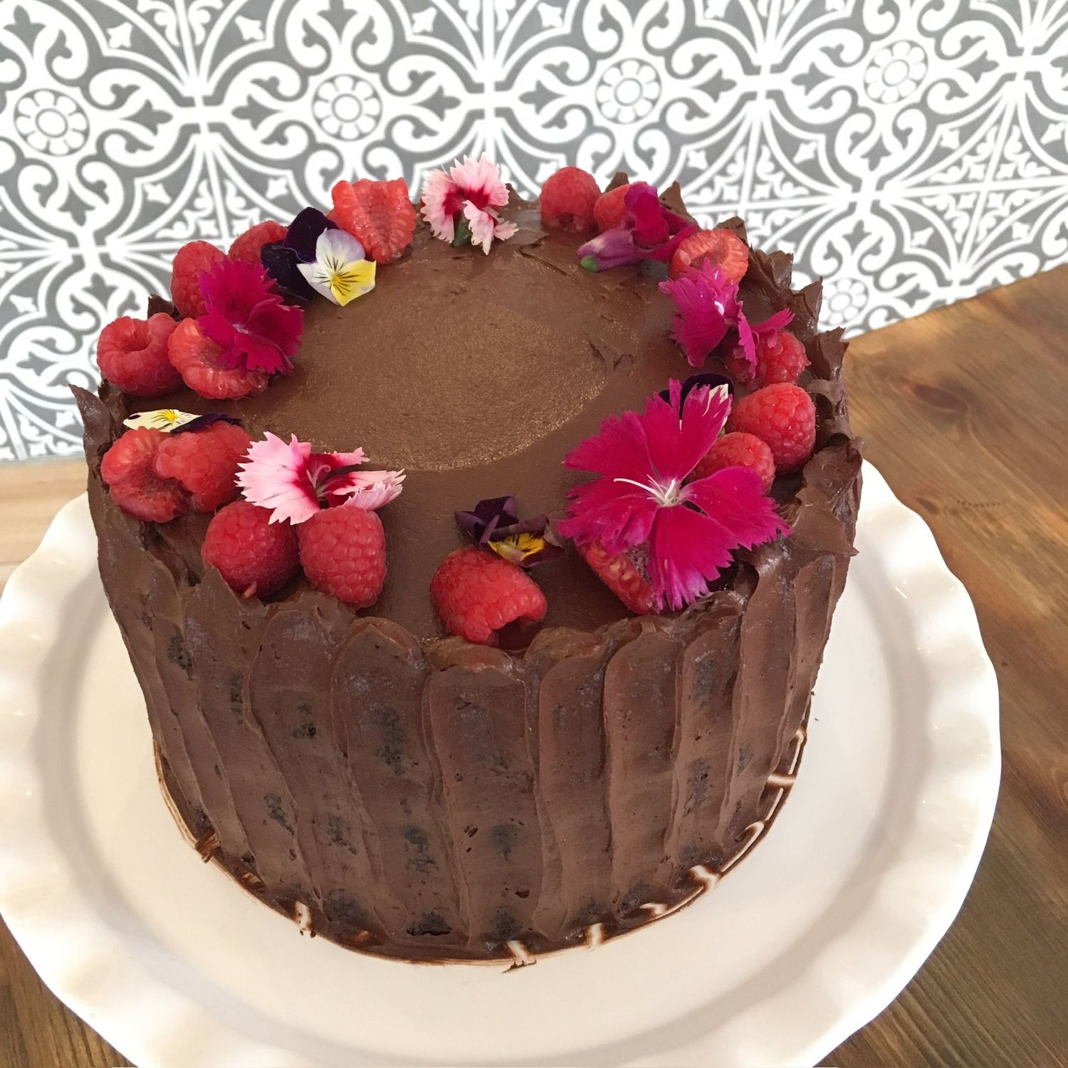 Chocolate Raspberry - A perfect pairing of fruit and chocolate, featuring house-made raspberry jam, a whipped chocolate frosting and topped with fresh raspberries and edible flowers.