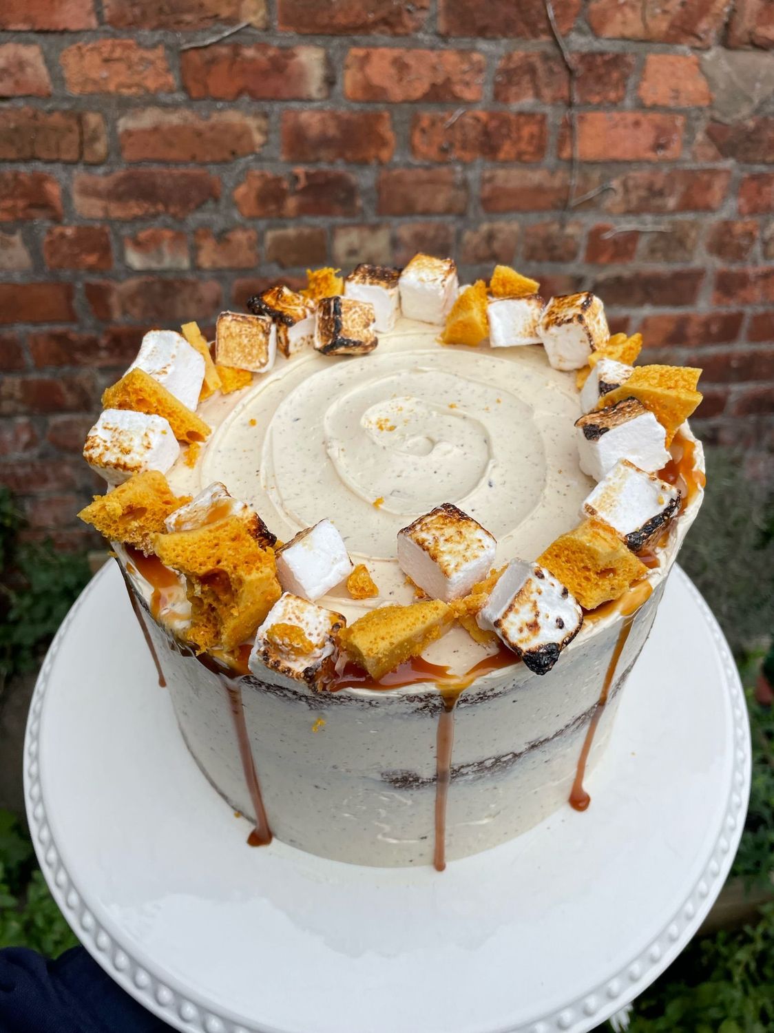 Sticky Toffee Cake - A proper showstopper and one of our best-sellers! This indulgent cake features rich date sponge layers, sandwiched with salted caramel and iced in a velvety salted caramel buttercream. It’s topped with house made toasted marshmallows, shards of golden honeycomb, a generous caramel drip, and finished with edible flowers. A dreamy choice for caramel lovers and guaranteed to turn heads.