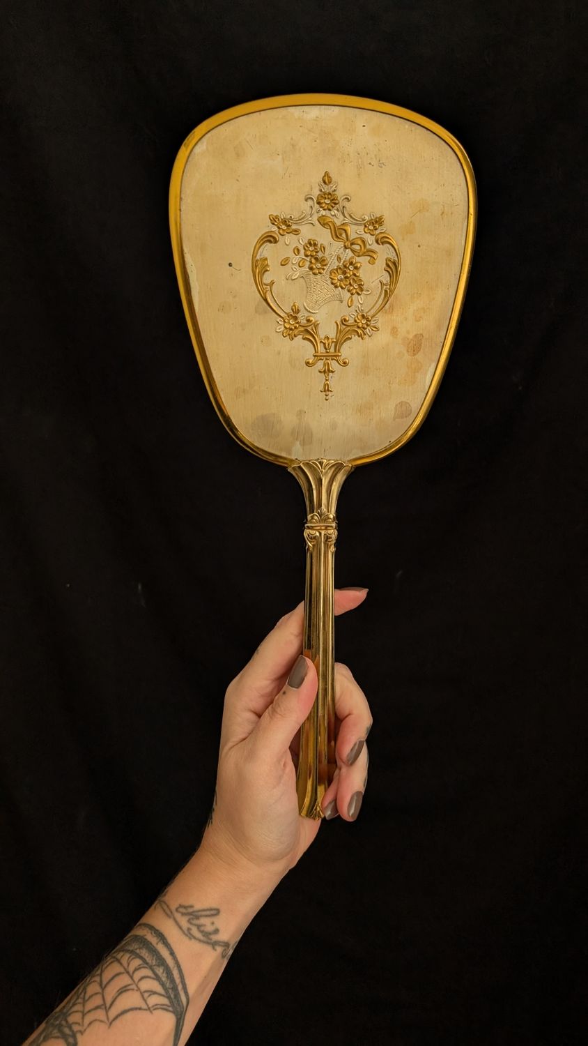 Gold colored hand held mirror with flower basket