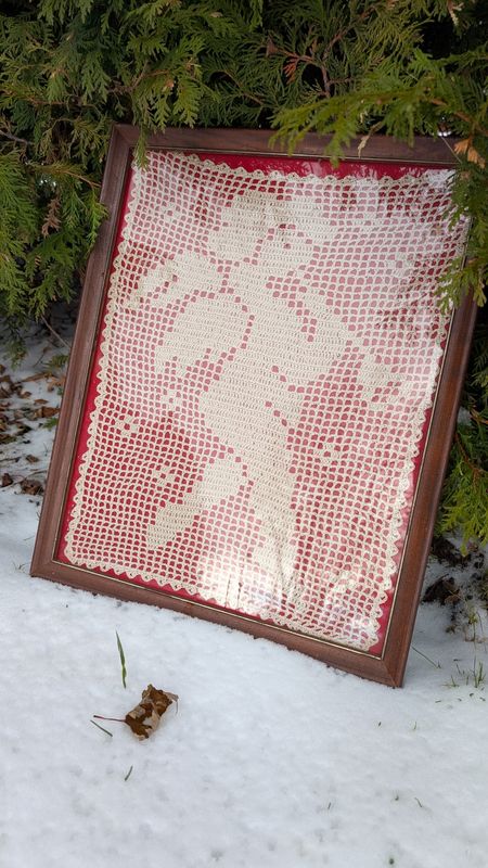 Framed crochet cherub on red background