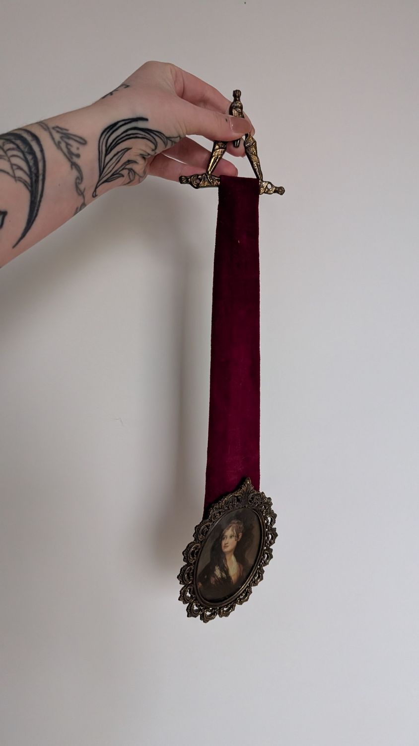 Oval ornate frame with large red velvet ribbon