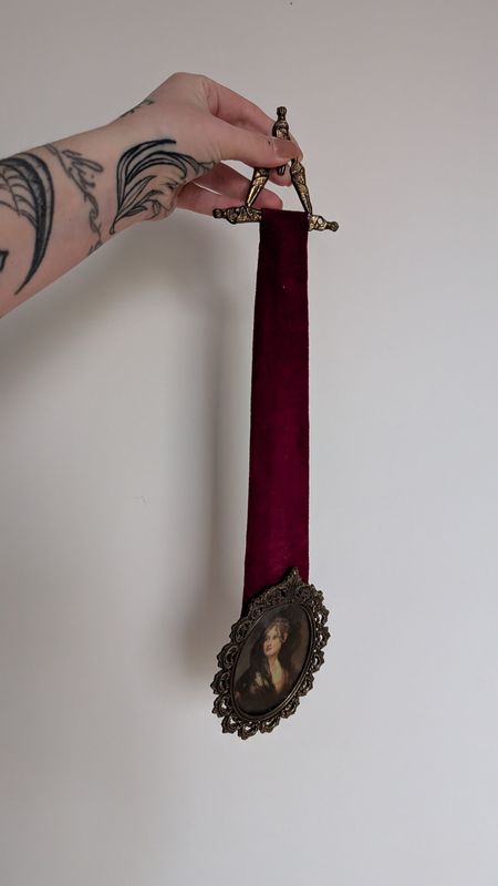 Oval ornate frame with large red velvet ribbon