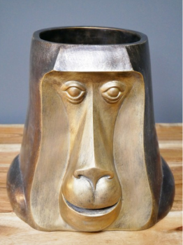 Golden finish pot in shape of a monkey's head
Sited in doors on wooden surface