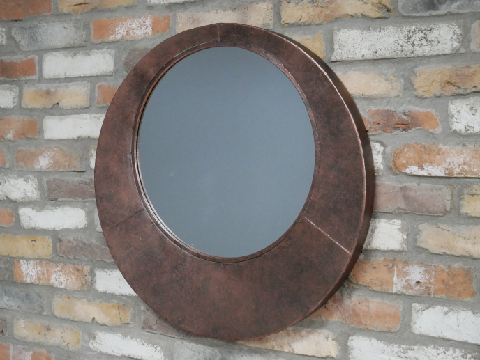 Round wall mirror with a wide textured metal frame in an aged bronze finish, featuring a clean circular mirrored centre.
