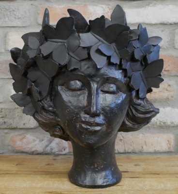 Josephina Black Finish Head Planted. 
She has closed eyes and ivy wreath - completely finished in black.
Sited against a brick wall and on a wooden surface