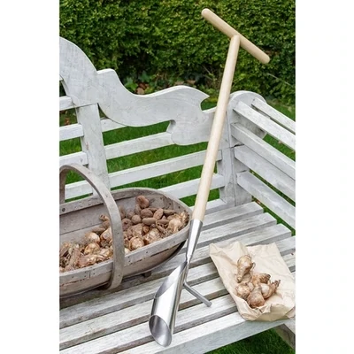 Long handled Garden Bulb Planter set against a white garden bench and wooden trug with bulbs in.