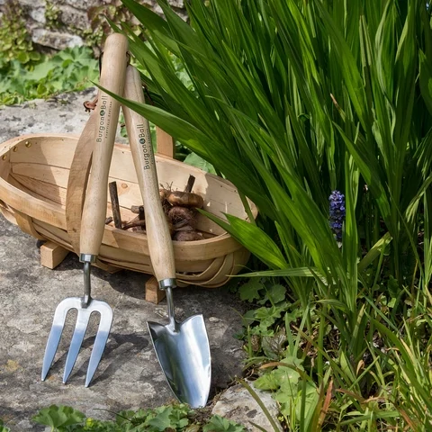 Mid Length Wooden Handled Fork and Trowel set against a wooden trug in garden setting