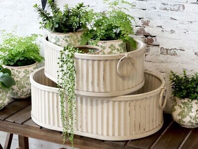 Set of two oblong grooved planters with handles.
Finish is Antique Cream.
Stacked in this image with two smaller pot plants and plants in the top planter.