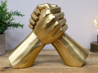 Two golden hands in clasp in a hand wrestling position,
Close up on shelf view.
17 cm tall