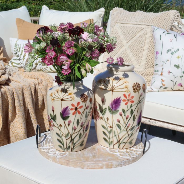 Set of Two Lea Floral Vases
Cream with wildflower painted design in pinks and mauves and green leaves
Set on a table on a summers day with a sofa dressed with throws and cushions