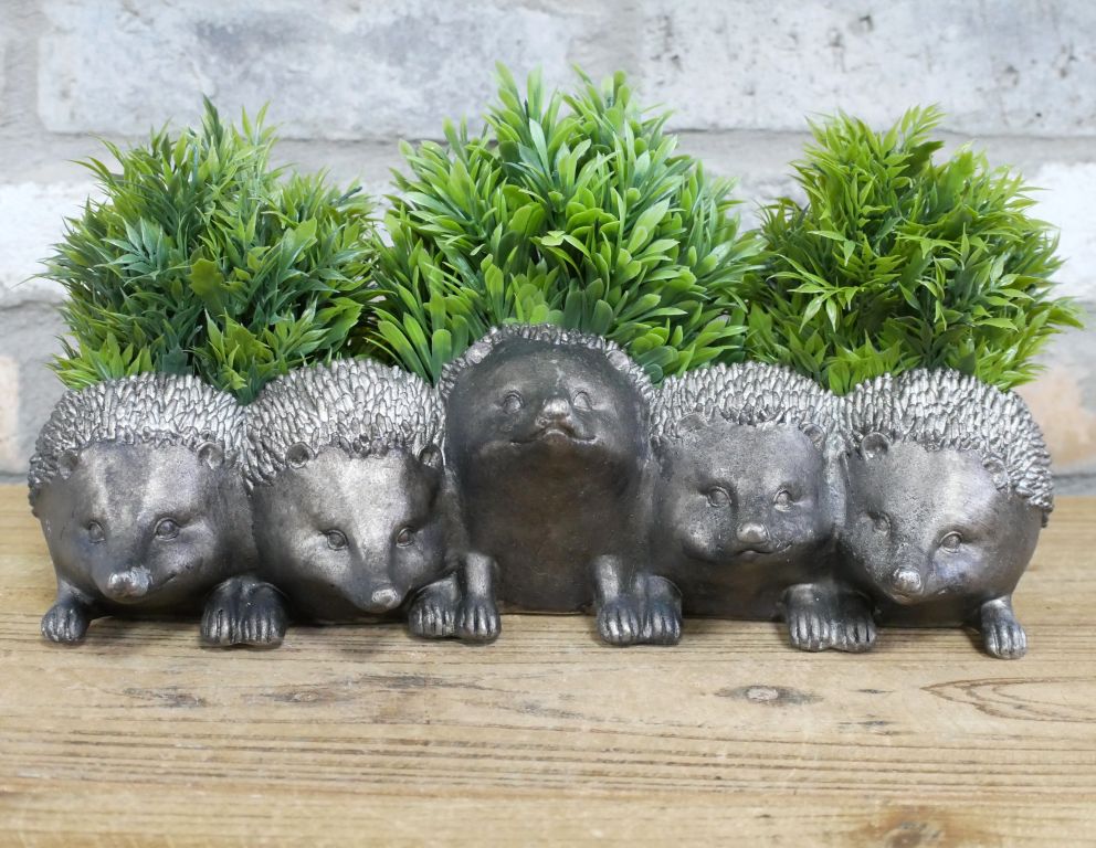 Row of five hedgehog-shaped metal planters with a weathered grey finish, each topped with dense green foliage.