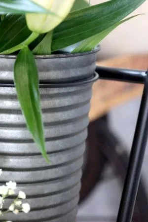 Tall black metal florist stand with a tiered frame holding six ribbed metal buckets