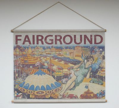 Fabric wall hanging showing a vintage fairground scene with rides, tents, and figures, topped with the word “FAIRGROUND”