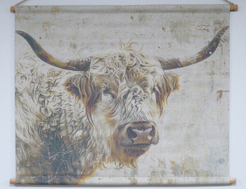 Fabric wall hanging showing a painted Highland cow with long curved horns and shaggy fur on a textured neutral background.