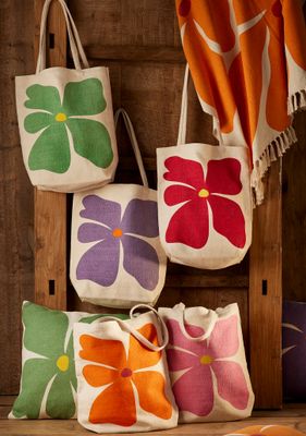 Canvas tote bags with bold flower prints in green, purple, red, orange and pink.