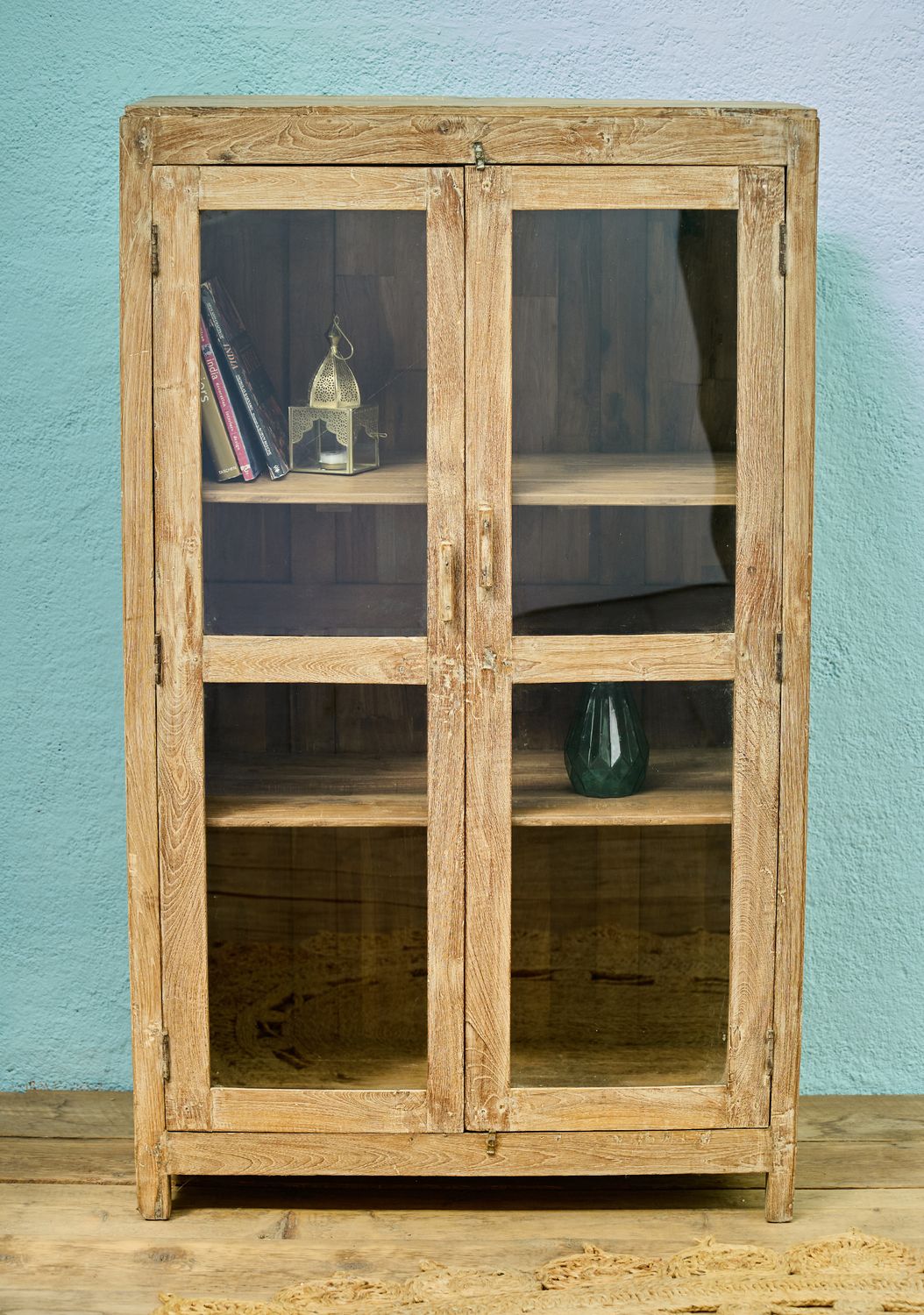 Wooden display cabinet with double glass doors and internal shelves, finished in a natural, lightly weathered wood tone.