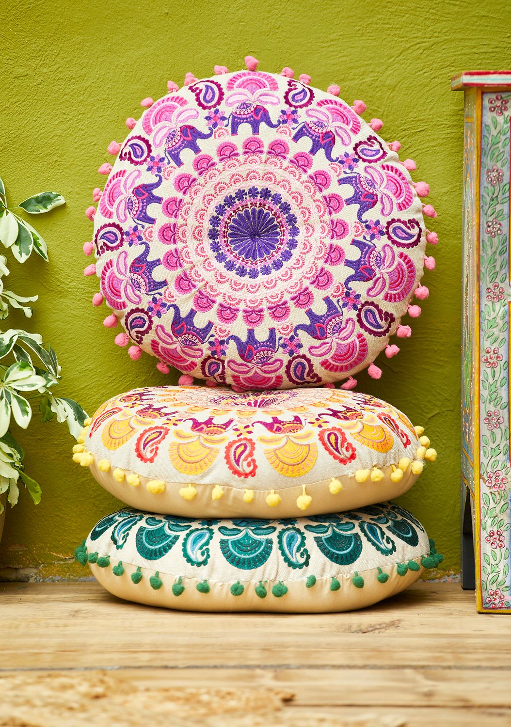 Round embroidered mandala cushions with elephant and floral patterns, finished with small pom pom edging