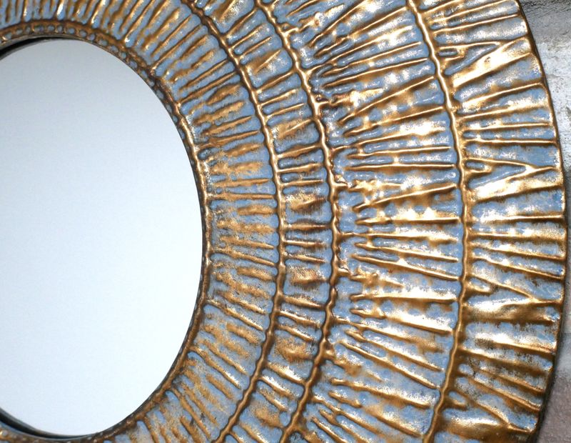 Round decorative wall mirror with a textured blue and gold metallic frame featuring concentric rings and raised radial detail