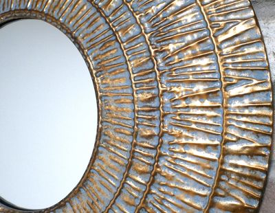 Round decorative wall mirror with a textured blue and gold metallic frame featuring concentric rings and raised radial detail