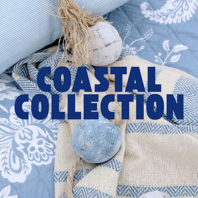 Coastal-themed home décor featuring blue and white textiles with decorative fishing floats and nautical accents.