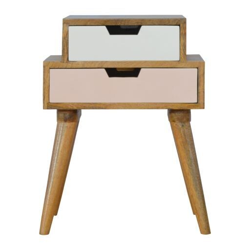 Blush pink and white stacked bedside cabinet with two offset drawers, natural wood frame, and tapered wooden legs on a white 