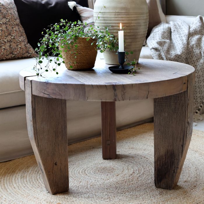 A rustic round wooden stool with a thick top and three sturdy legs.