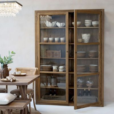 Tall wooden display cabinet with glass doors and internal shelving, designed to showcase decorative items.
