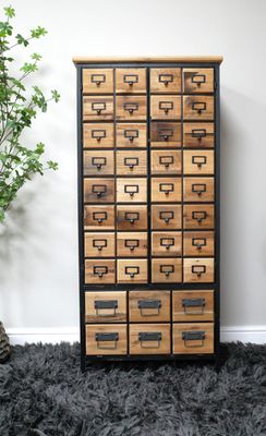 Drawerful drawer storage cabinet.  many drawers with natural finish fronts and black metal labels. black frame.