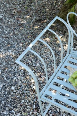 Metal garden bench with an arched back and decorative curved detailing, offering a light, elegant design suited to outdoors,