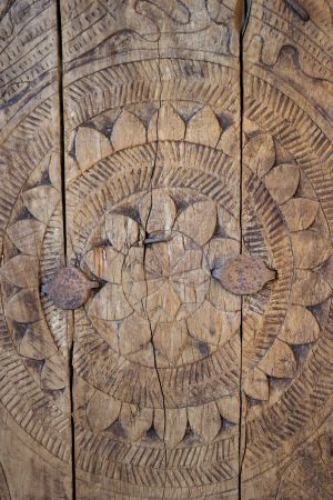 Antique Indian village door with intricate hand-carved patterns, weathered wood and aged patina.