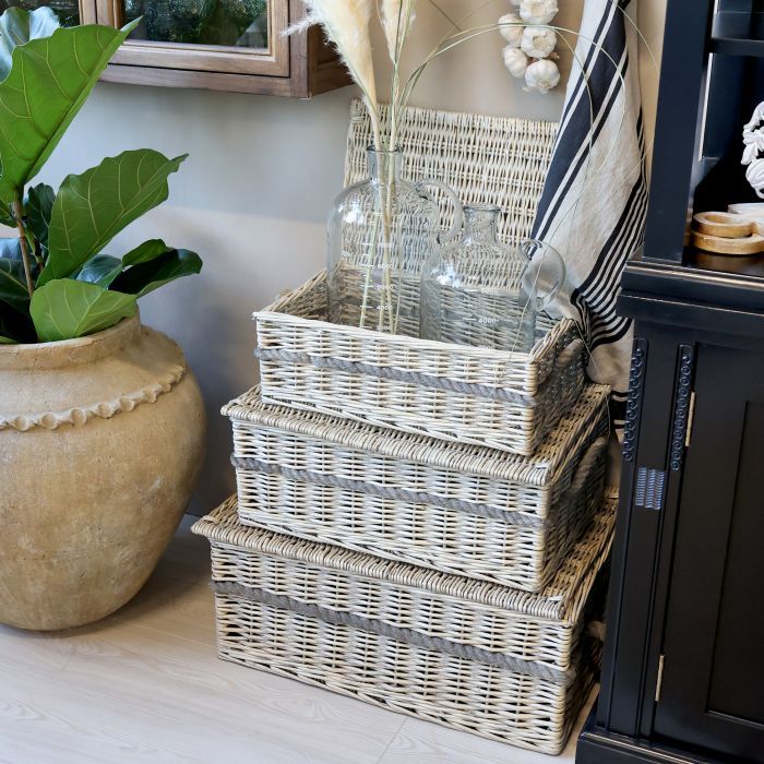 Set of three woven willow storage baskets with lids and rope handles in graduated sizes, ideal for organising household items