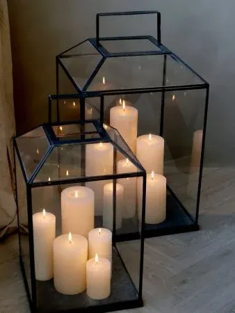 Clear glass lantern with black metal frame and handle, designed to hold a candle and add soft ambient light.