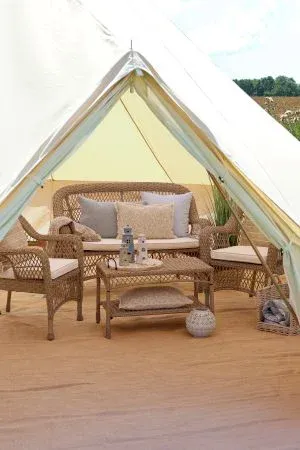 Woven rattan furniture set with sofa, two armchairs, cushions and coffee table, ideal for relaxed indoor or covered outdoor