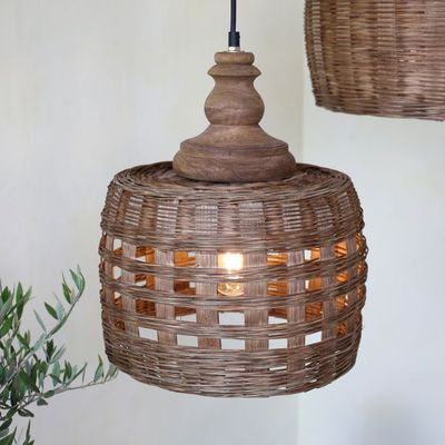 Woven rattan pendant light with turned wood detail, casting soft patterned light, ideal for natural, relaxed interiors