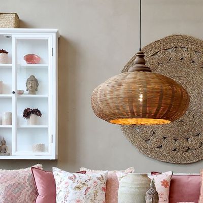 Handwoven rattan ceiling light with a rounded shade, casting a soft, warm glow through its natural woven pattern